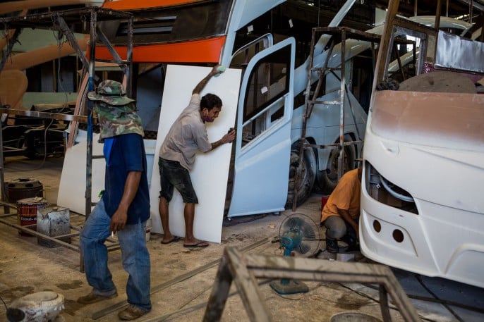Workers at Mee Saeng Bus Body assemble panels and doors for tour buses they will later paint.